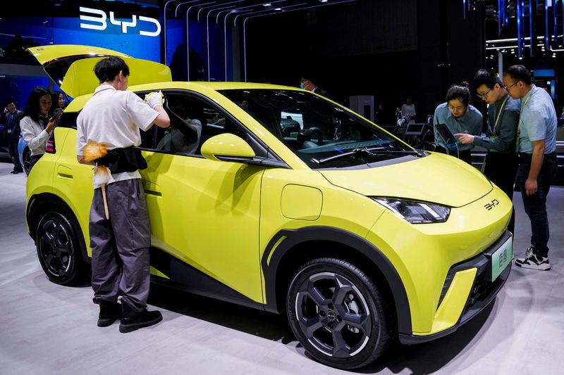 FILE PHOTO: People use their phones in front of the BYD Seagull that is displayed at the Auto Shanghai show, in Shanghai, China April 19, 2023. REUTERS/Aly Song/File Photo