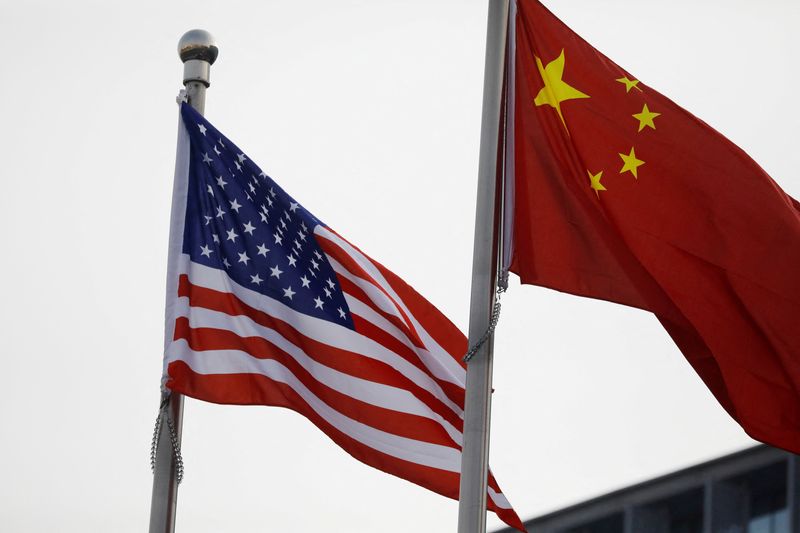 FILE PHOTO: Chinese and U.S. flags flutter outside the building of an American company in Beijing, China January 21, 2021. REUTERS/Tingshu Wang/File Photo