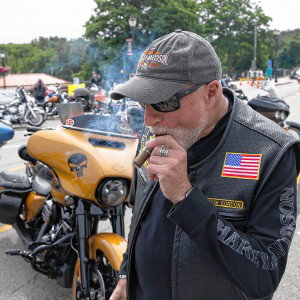 Jim Peyser lites up his cigar among the bikes along Lakeside Ave. at Weirs Beach on Tuesday, June 11, 2024.