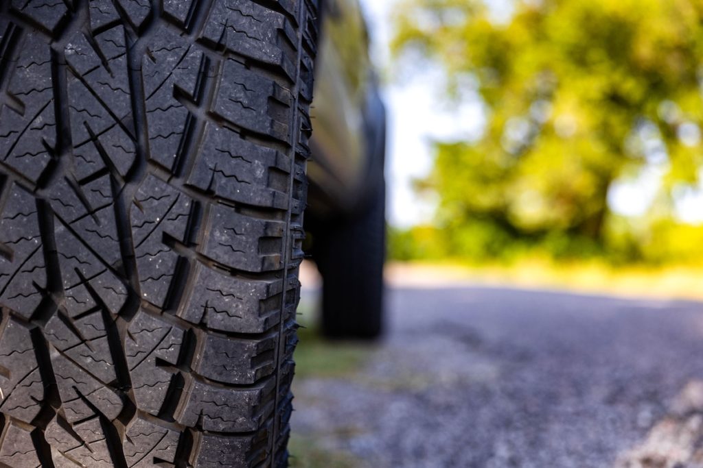 A side view of a sleek black vehicle tire on an asphalt road